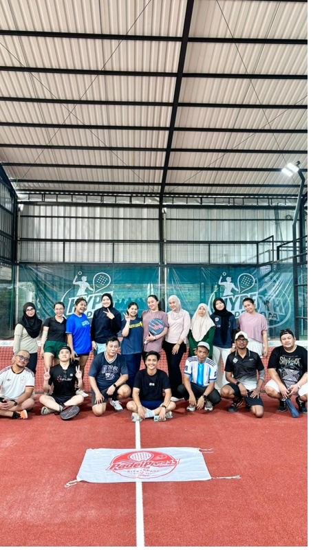 Komunitas PadelPress berpose dengan spanduk di lapangan Hype Padel Cibinong